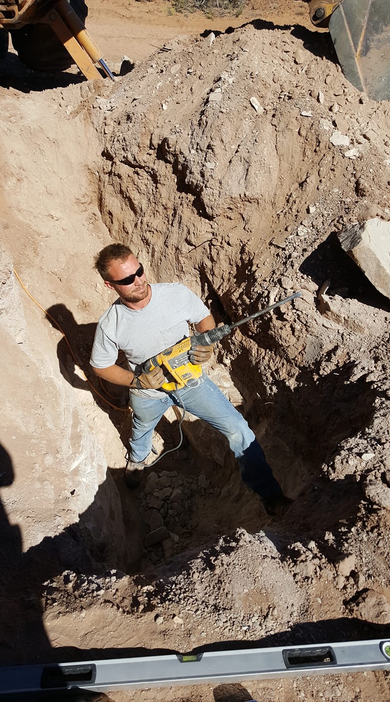 Rocky in a trench with a rotary hammer, excavator bucket overhead