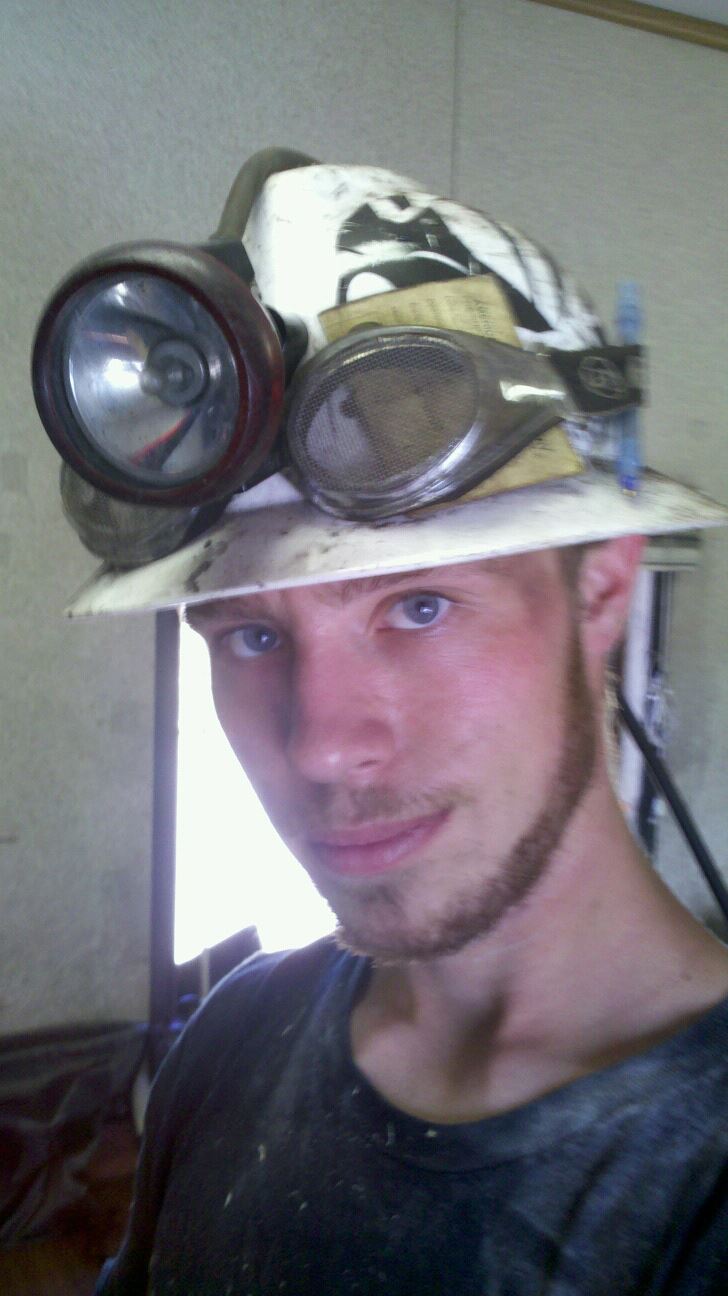 Portrait in a white hardhat with a carbide-style lamp and goggles